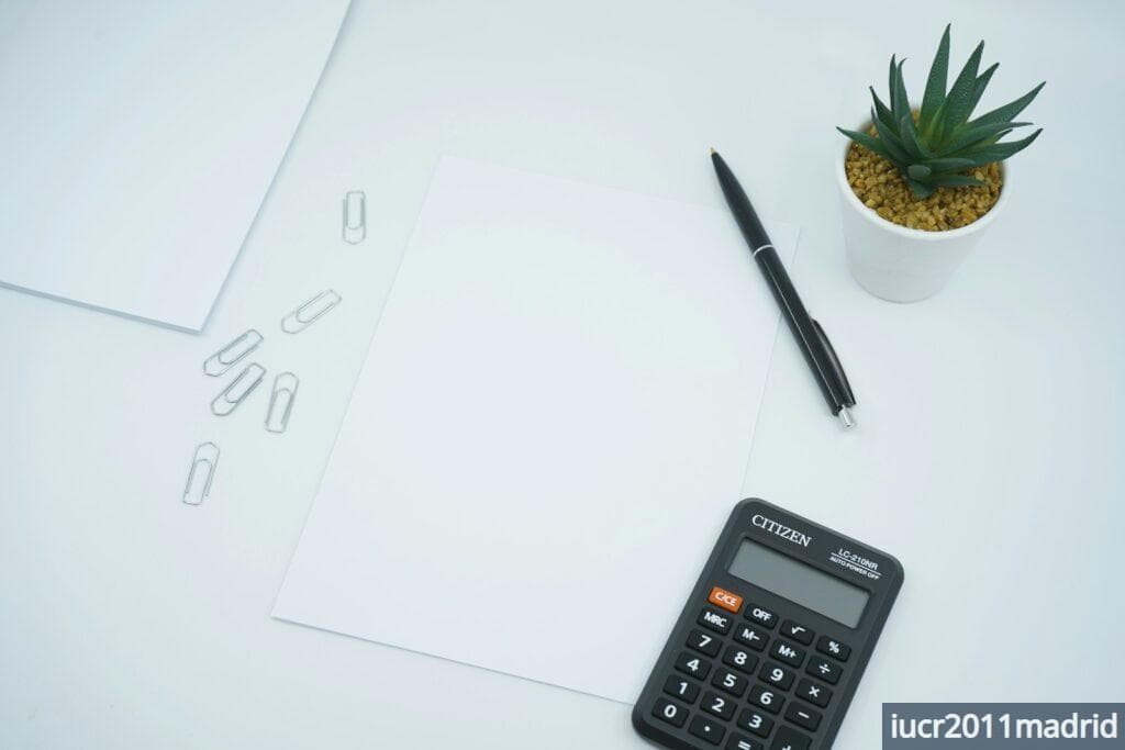 black calculator beside black pen on white printer paper