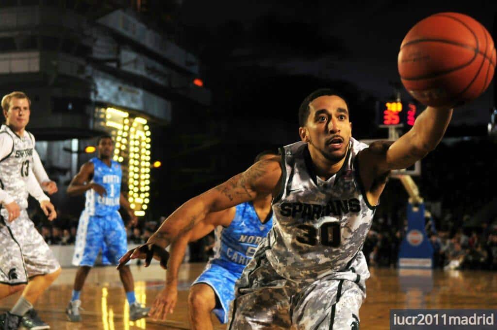 Intense basketball game with athletes in action on an outdoor court during nighttime.